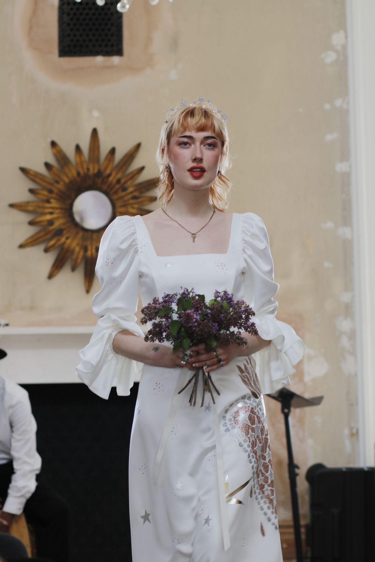 Elegant bridal fashion featuring a white square-neck dress with puff sleeves and purple bouquet.