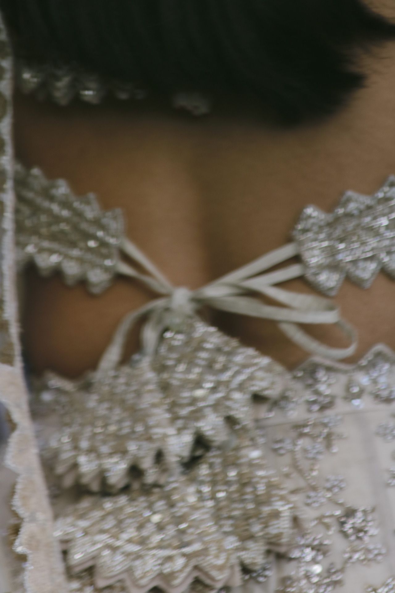 Close-up detail of delicate lace trim and ribbon on white wedding attire.