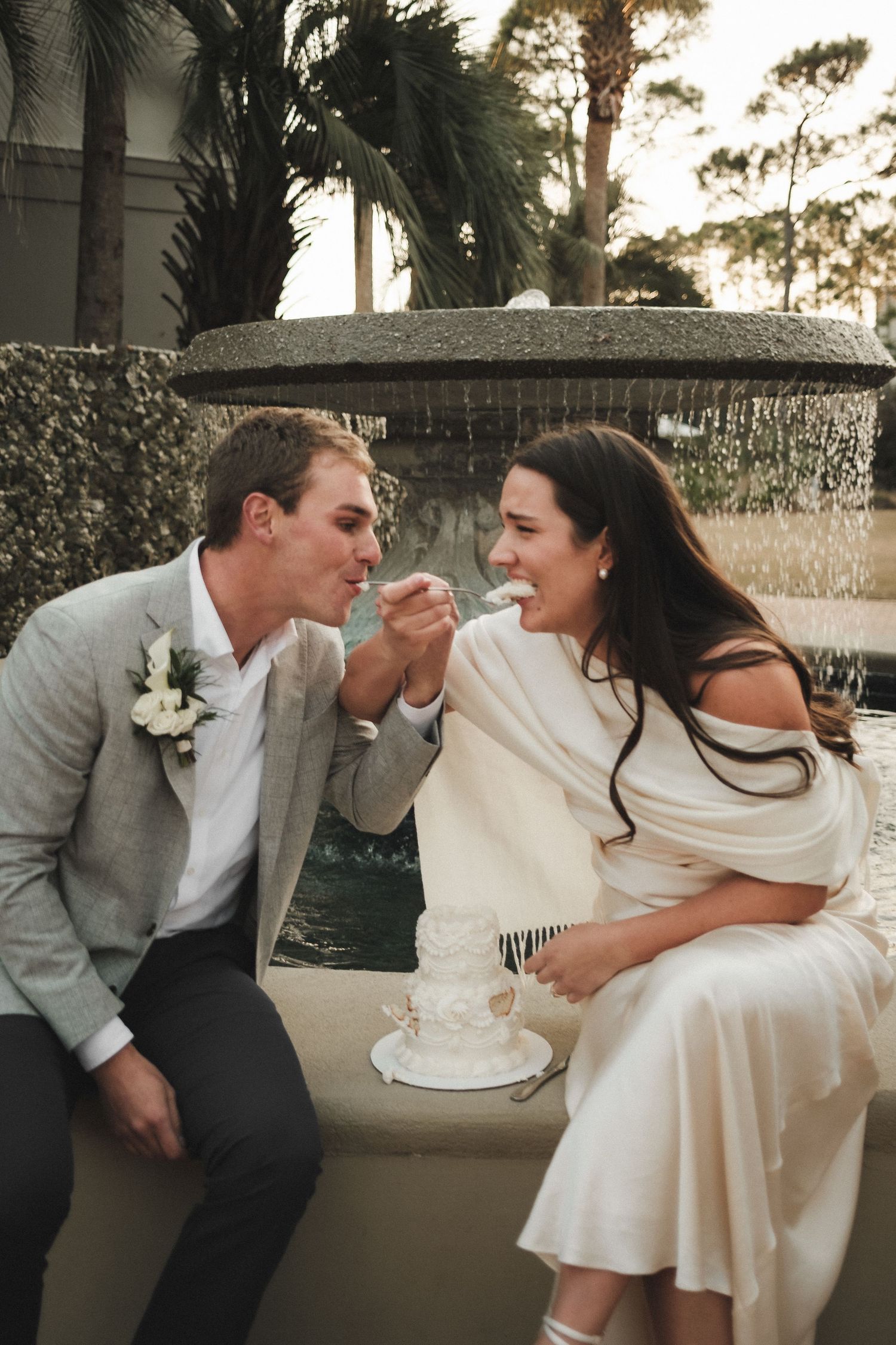 Newlyweds sharing cake in playful moment during wedding reception.