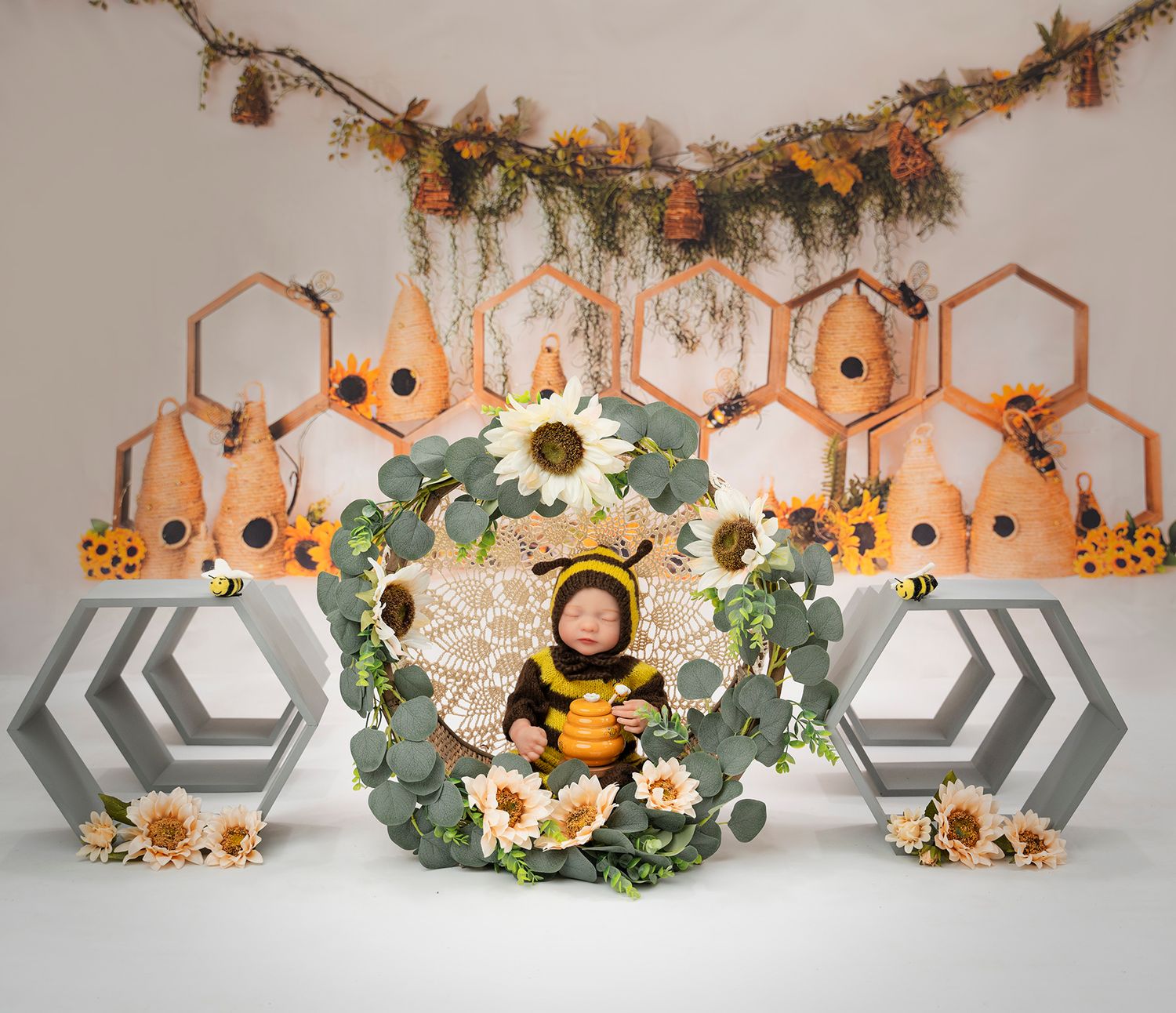 Whimsical nursery setup with honeycomb backdrop, sunflowers, and greenery in earth tones and warm lighting.