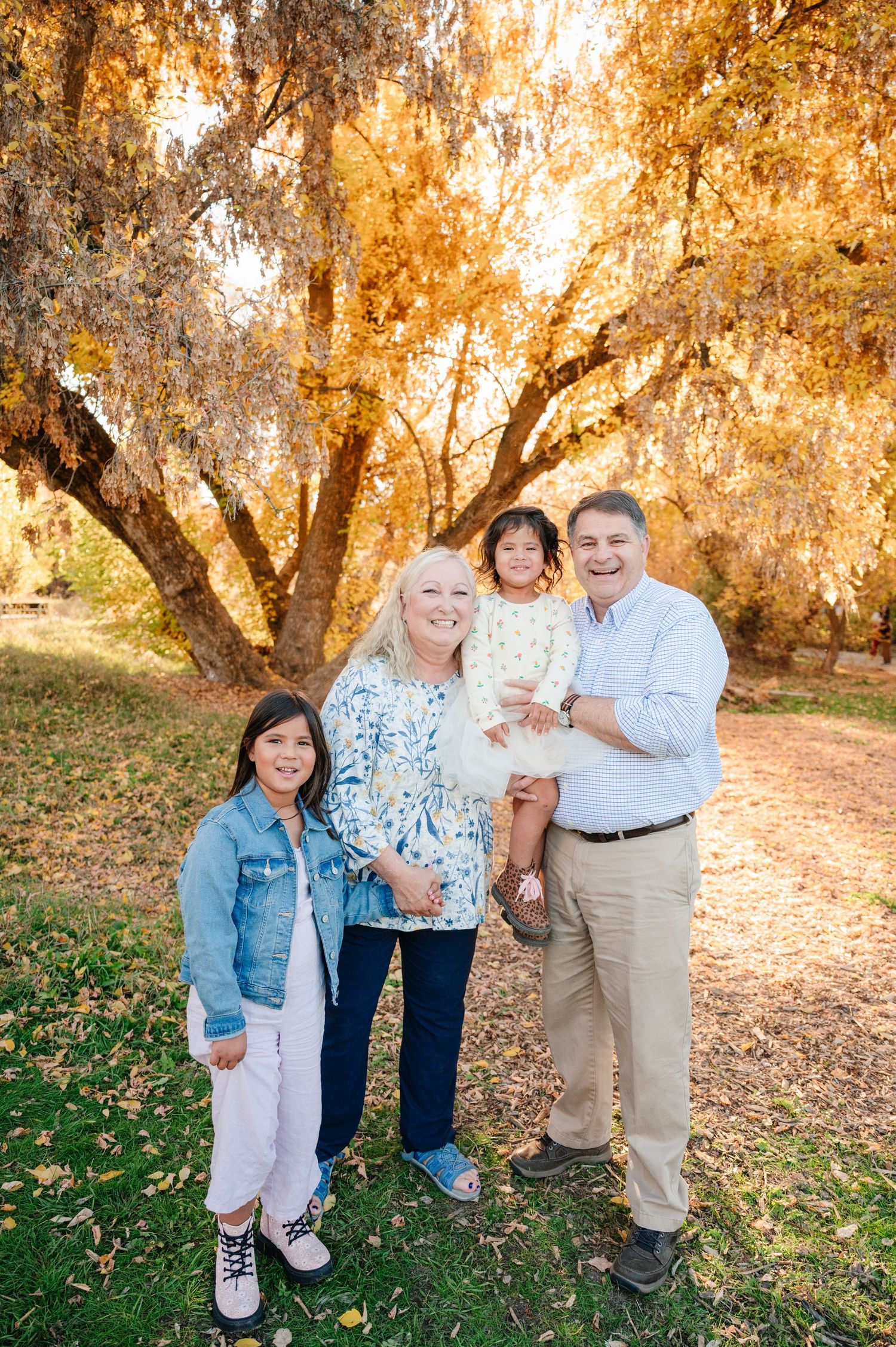 A group poses under warm-toned fall foliage in a park setting.