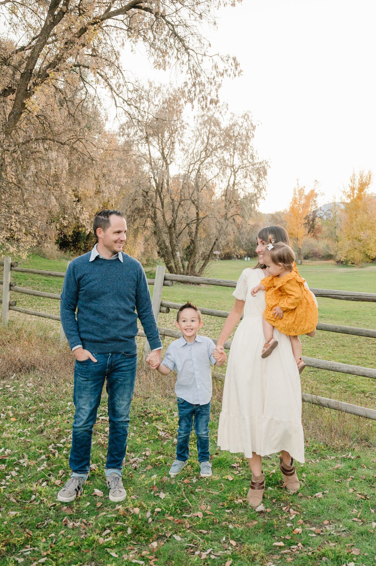 Family enjoying autumn day together by rustic fence in countryside setting.