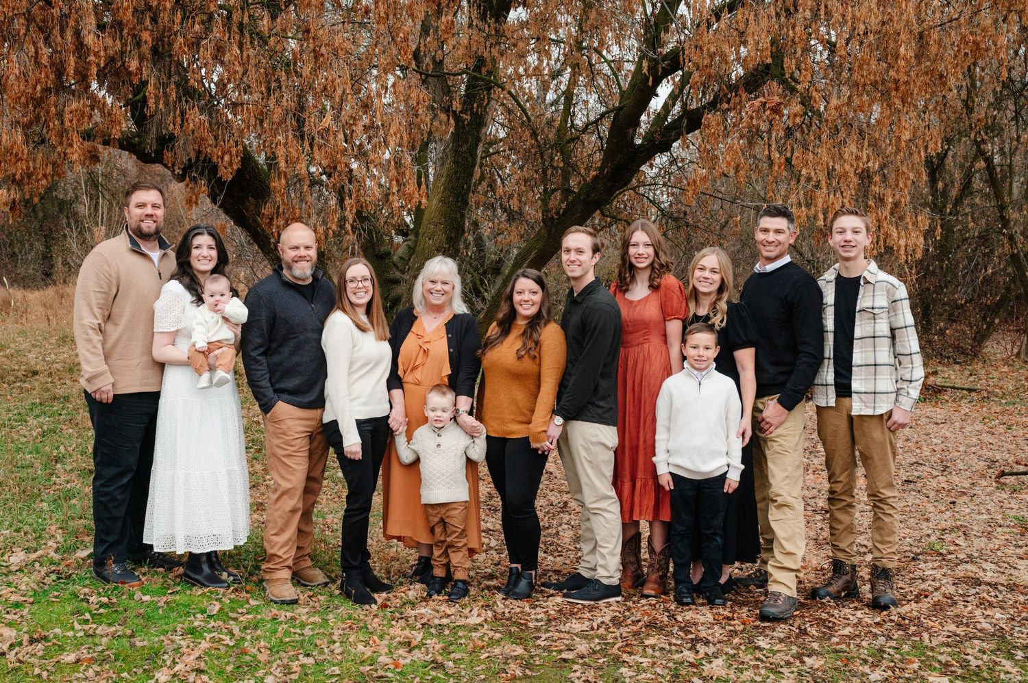 Large family group portrait in autumn setting with fall foliage.