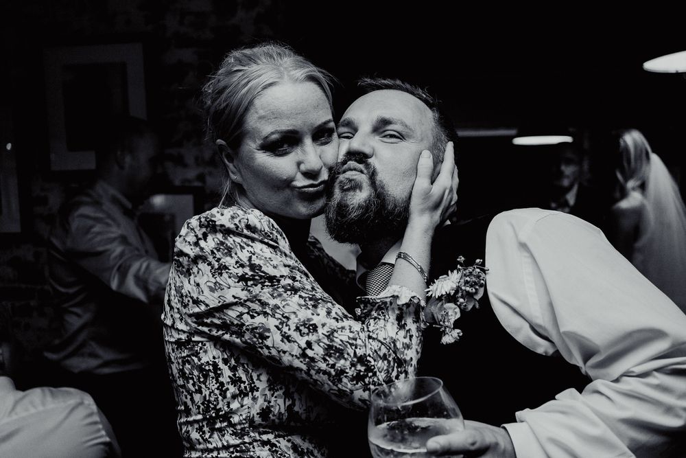 A candid black and white moment showing affection and laughter at a party or celebration.