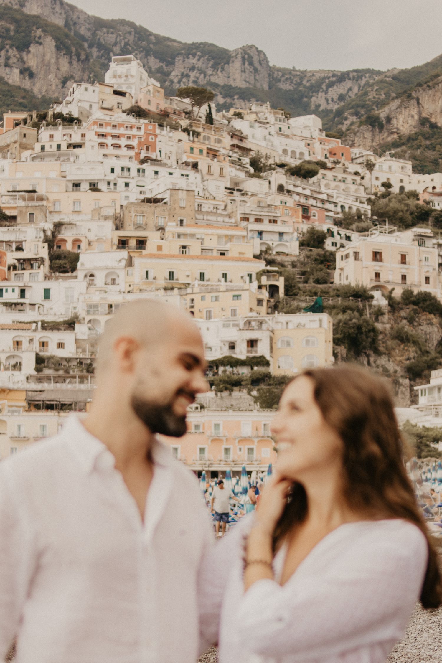 Intimate moment between couple with scenic Positano hillside architecture in background.