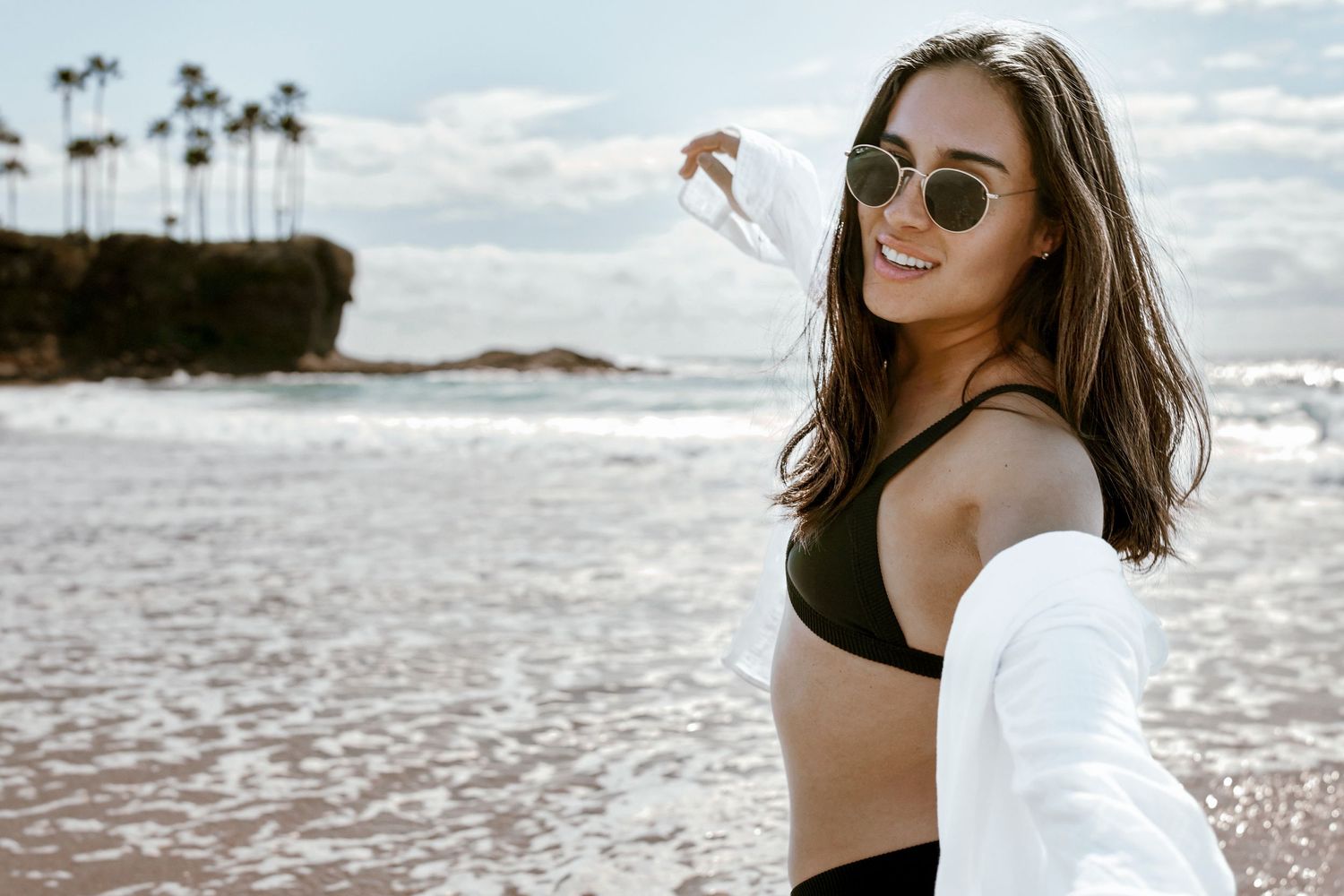 Beachside portrait with palm trees and ocean waves in background.