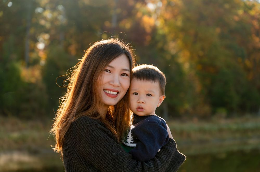 Mother and baby enjoying autumn sunset in outdoor portrait session.