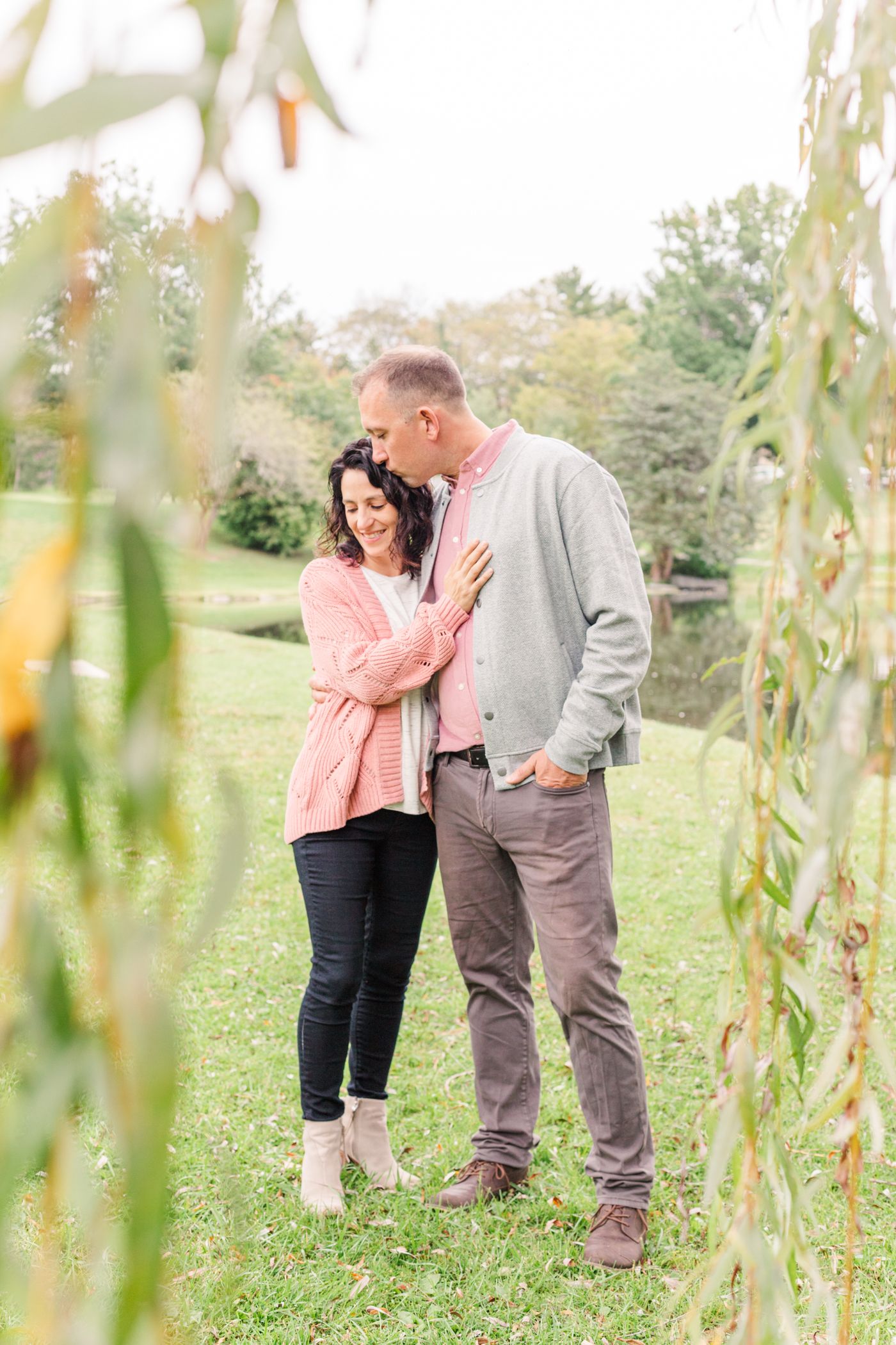 Man kissing woman under a willow tree during a family session in New Paltz, NY with Danielle Lauren Photography
