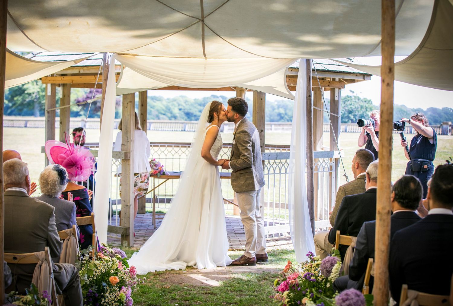 Wedding reception setup under a white tent with elegant table settings and decor.
