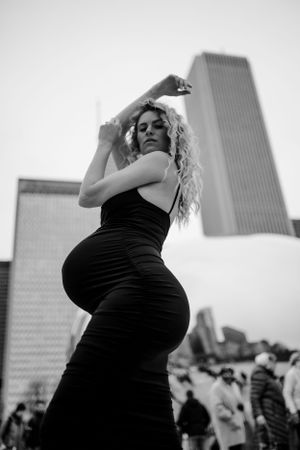 Artistic black and white photo of woman posing dramatically with skyscraper in background.
