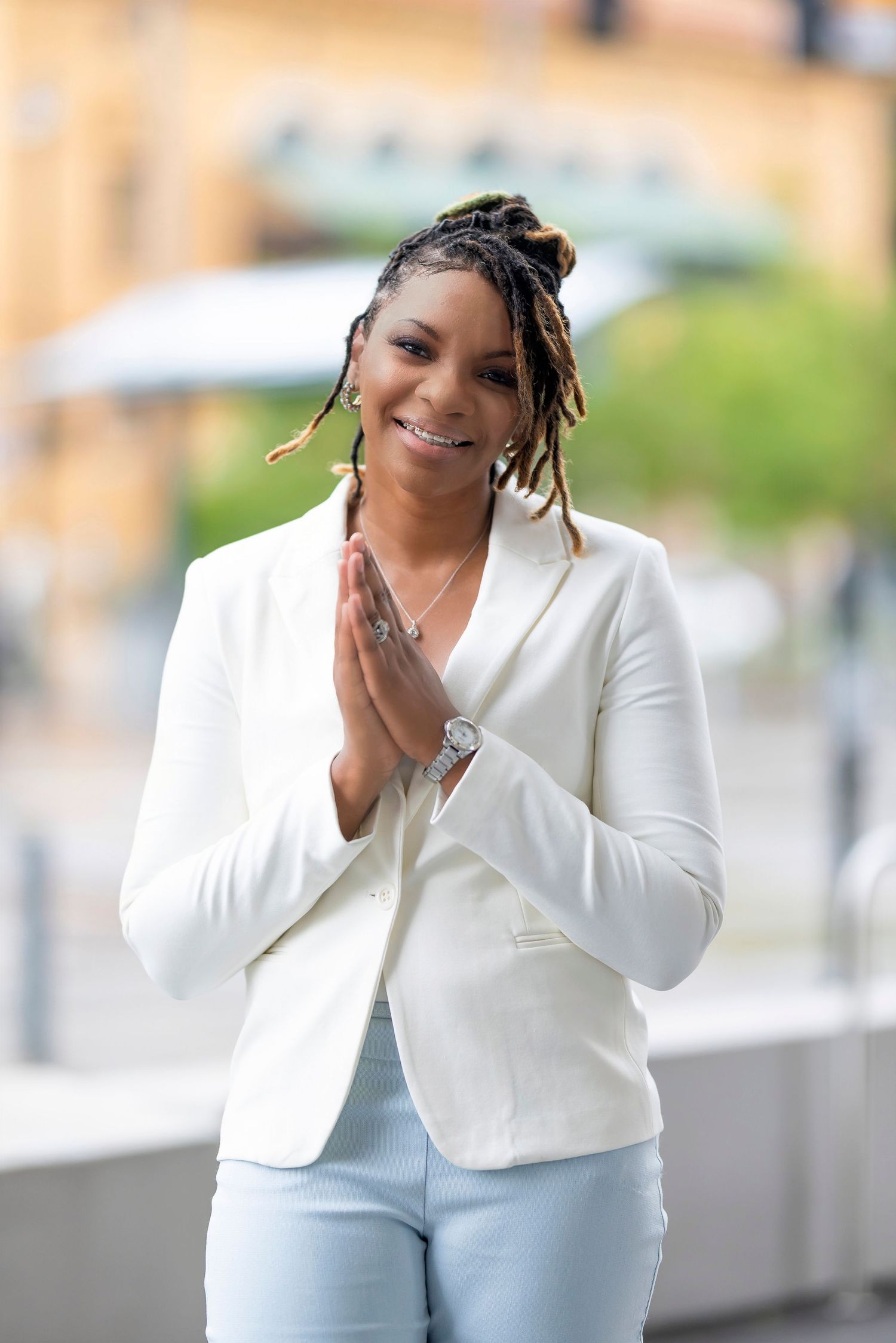 Professional in white blazer and light denim brings positive energy with a warm greeting pose.