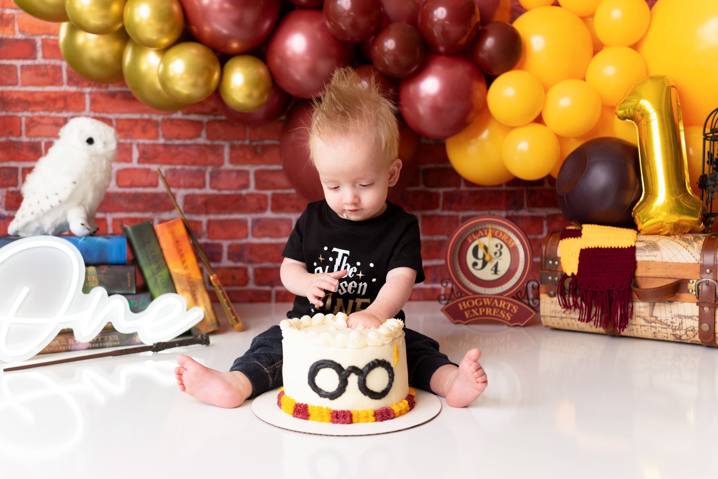 First birthday party scene with Harry Potter themed decorations and colorful balloon arch.