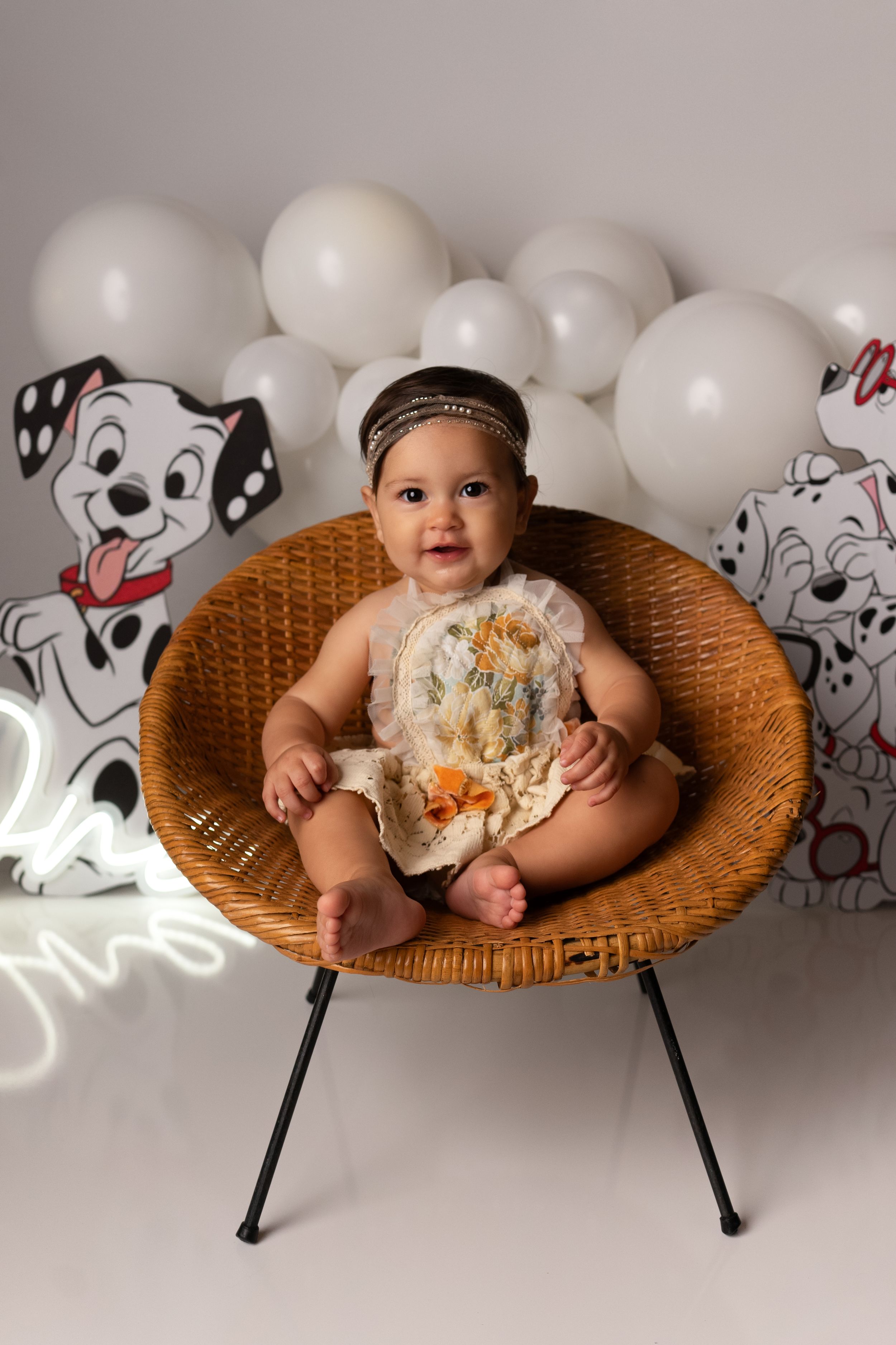 Wicker chair photo session with white balloons and dalmatian-themed decorative elements.