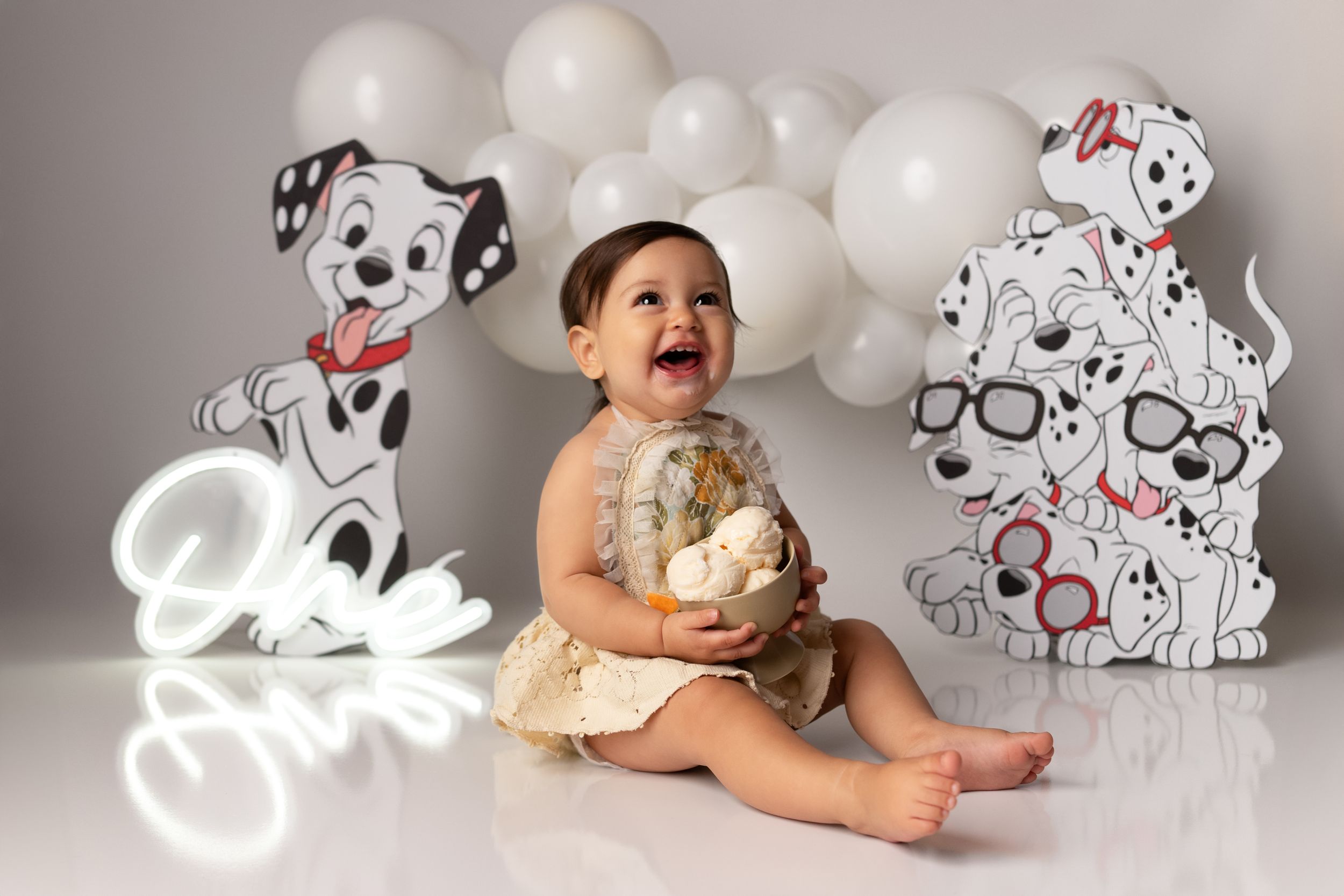First birthday cake smash with ice cream. Playful photo series with dalmatian-themed props and white balloon arrangements.