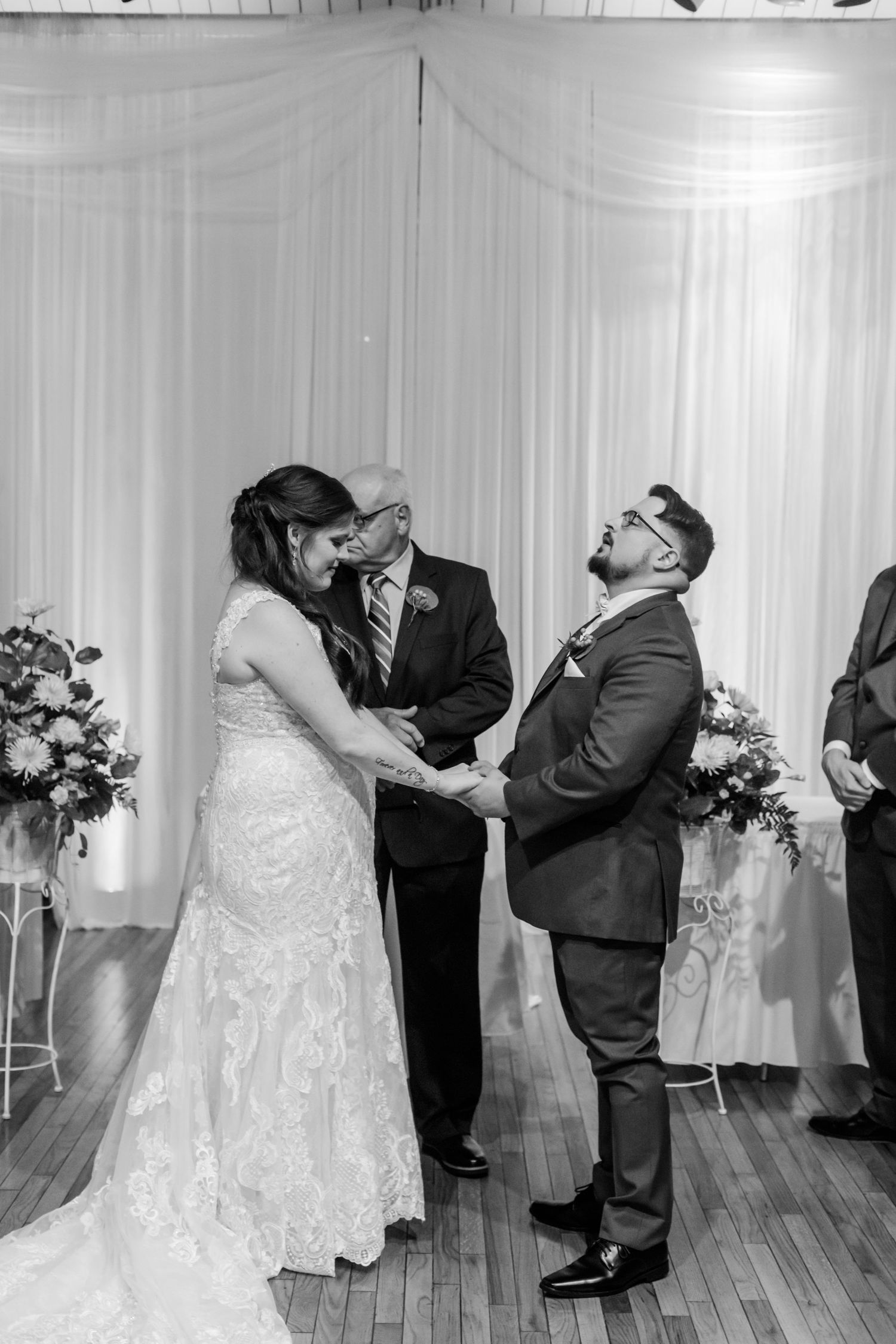 Black and white sequence of wedding ceremony moments on hardwood floor with white backdrop.