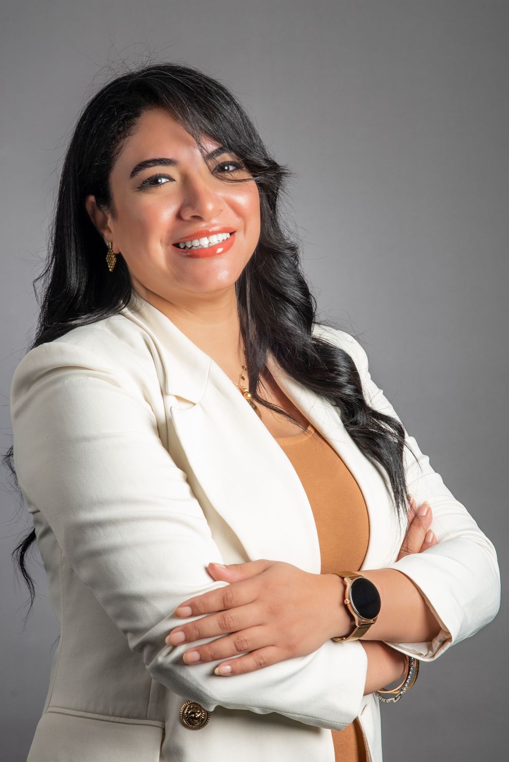 Professional headshot of a person in a white blazer with a warm smile.
