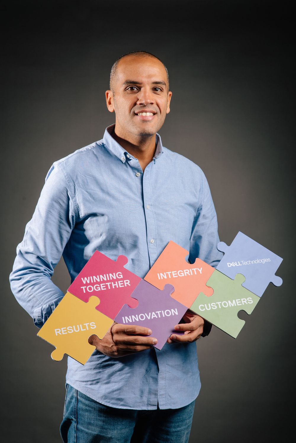Professional holding colorful puzzle pieces with values like Innovation and Winning Together.