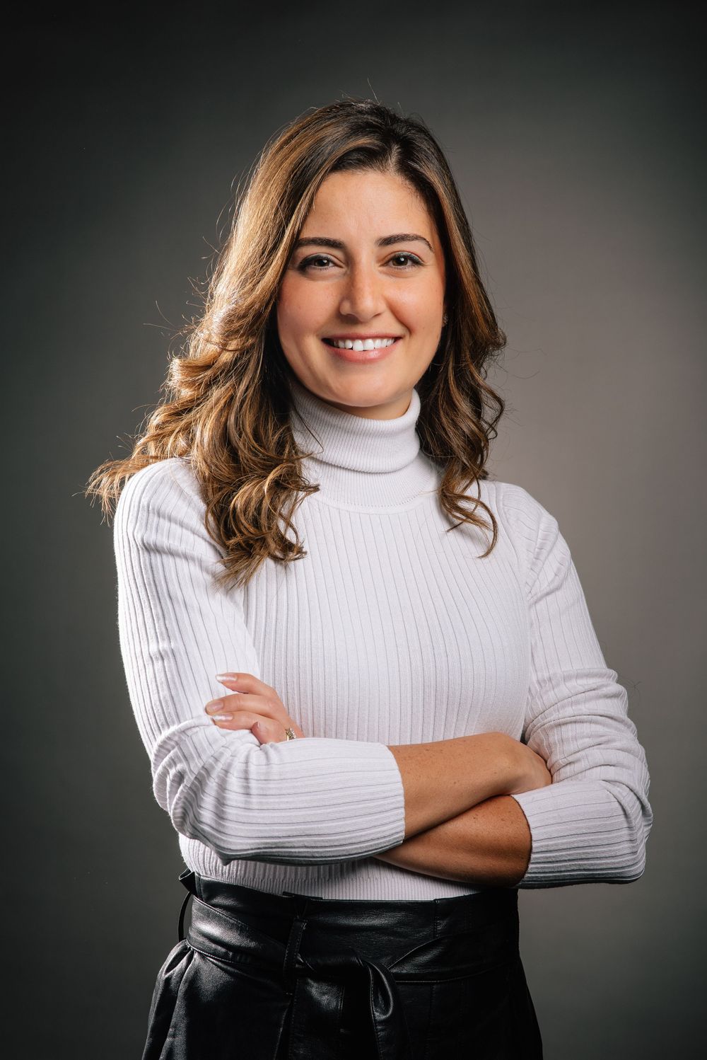 Professional studio portrait of a person in a white turtleneck sweater.