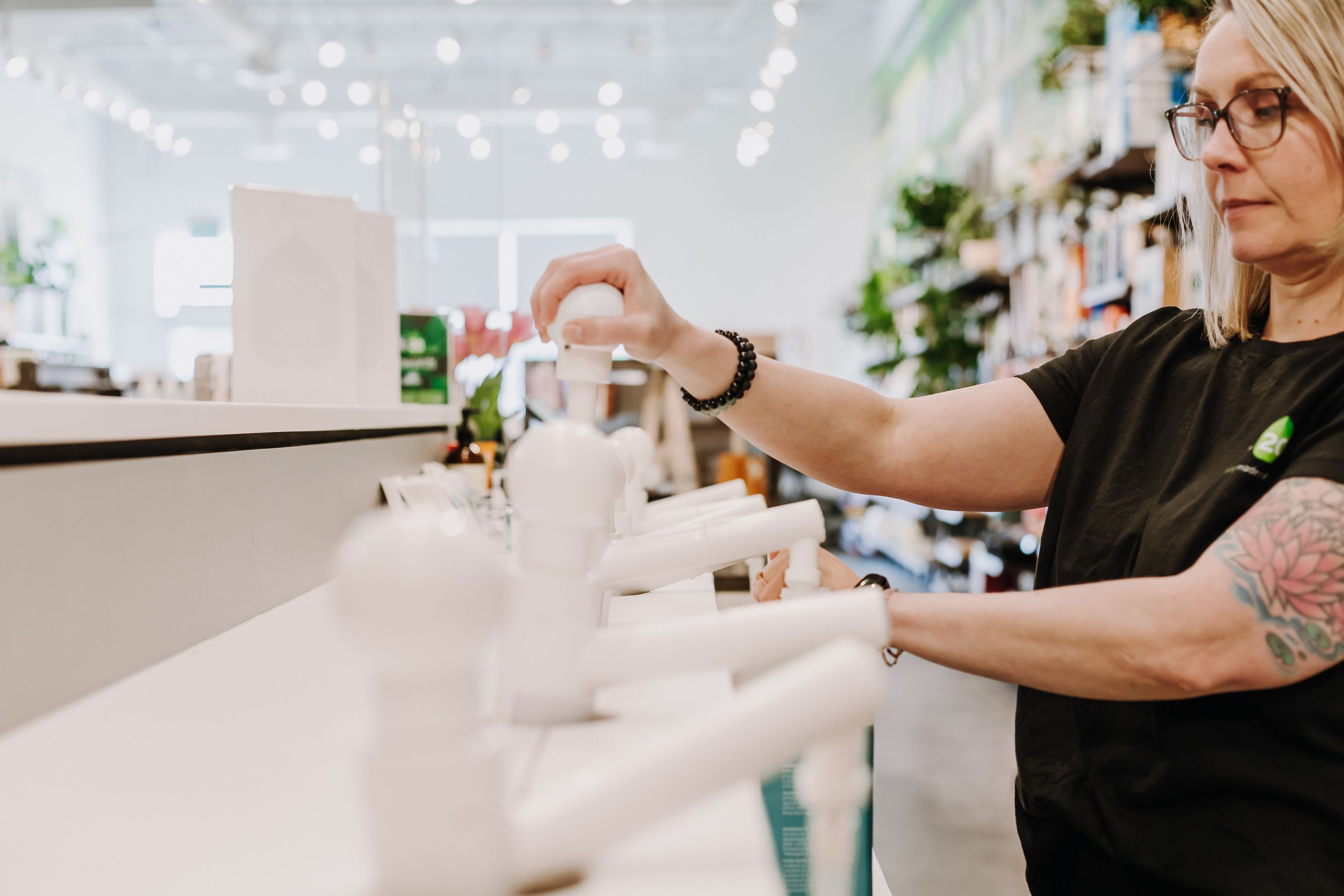 Tattooed arms arranging white product displays on modern retail counter.