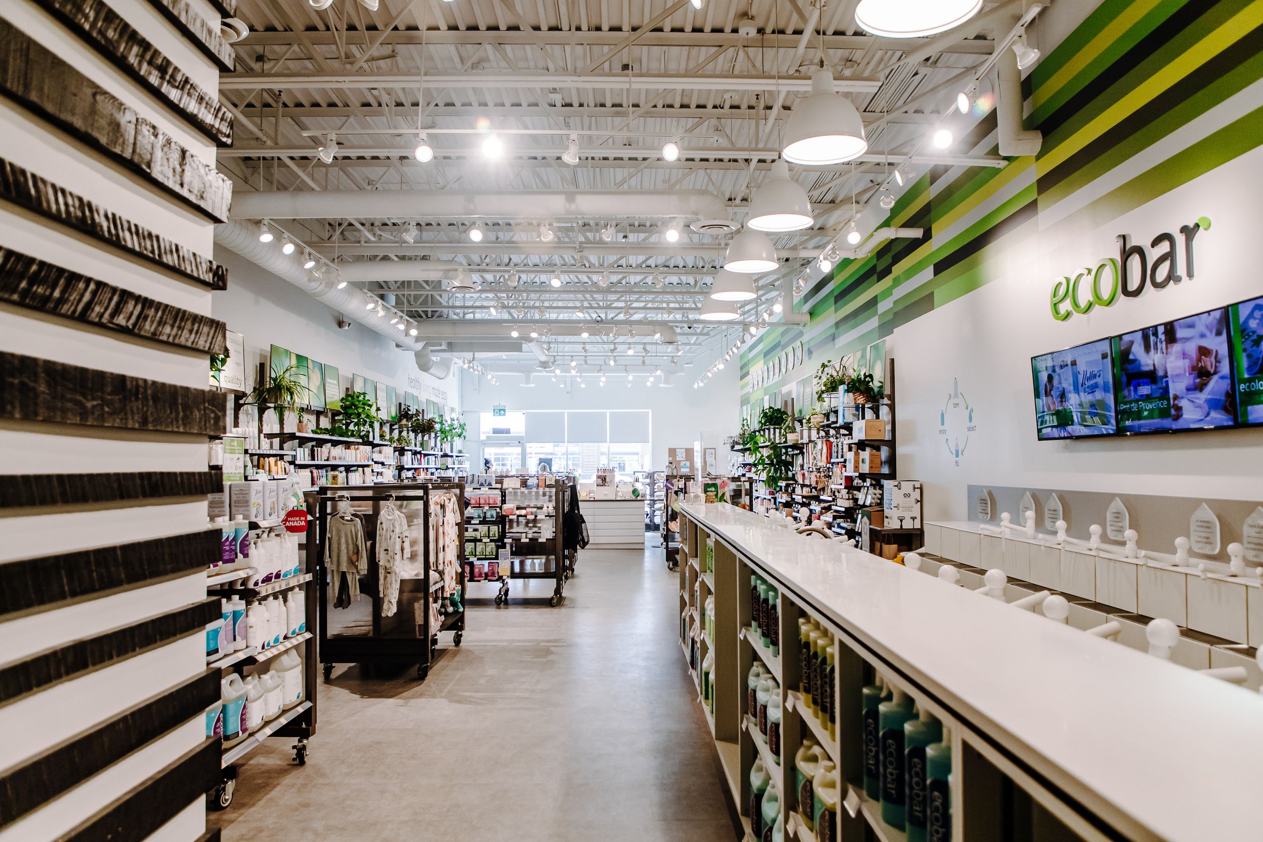 Modern retail store interior with white shelving, green accents and industrial ceiling.