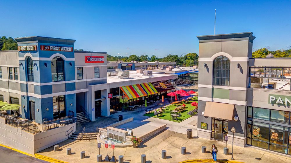 Modern retail plaza with Mediterranean-style architecture and outdoor dining spaces.