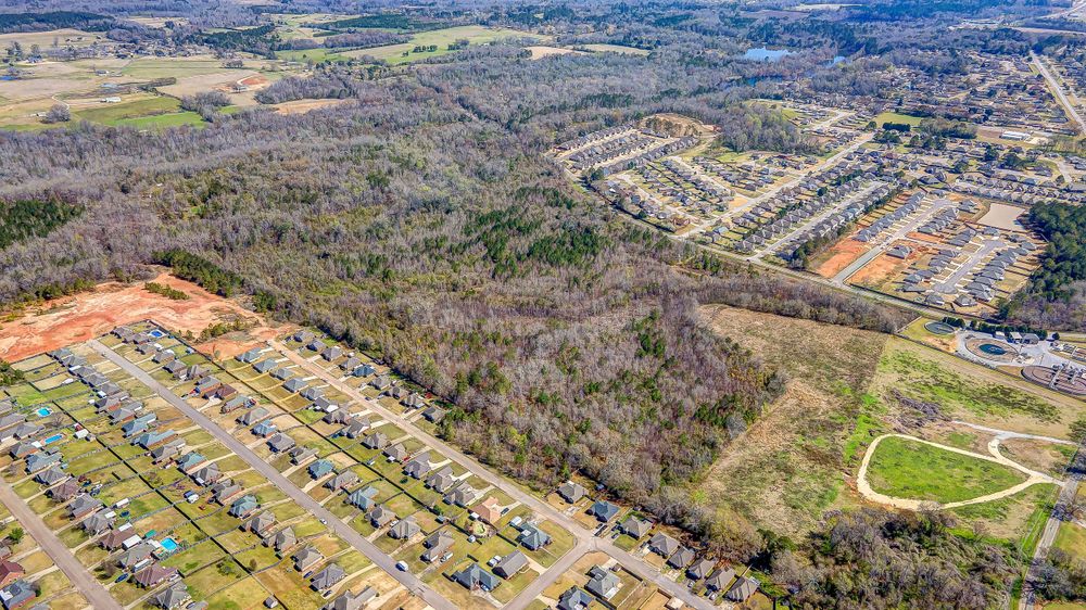 Aerial view showing residential development adjacent to wooded areas and undeveloped land.
