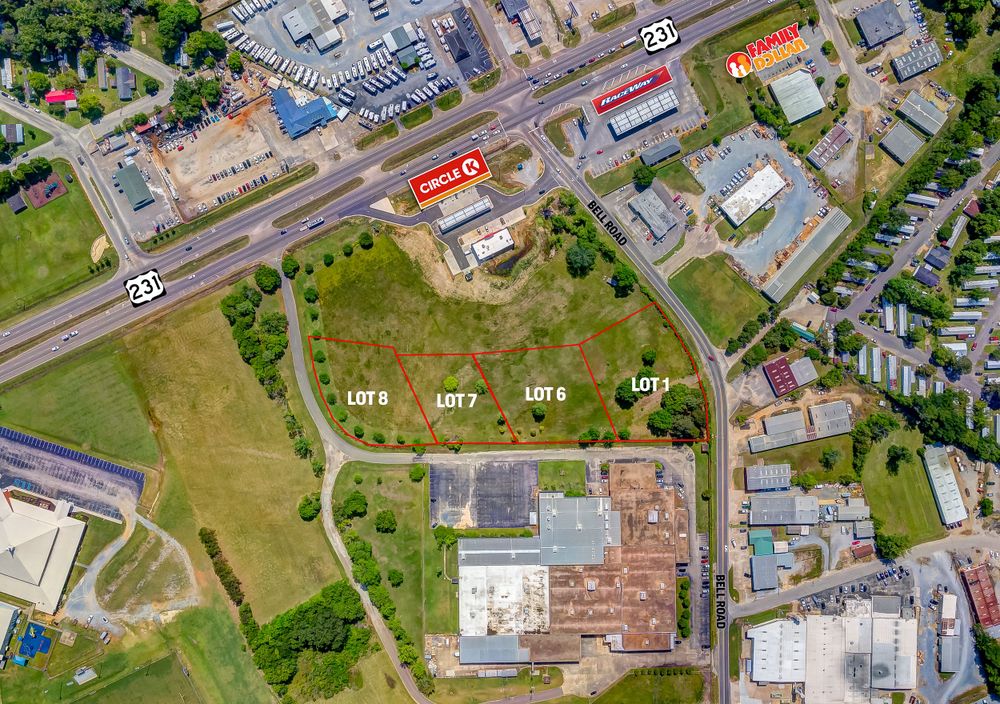 Aerial view of commercial development along highway with large undeveloped green space in center.