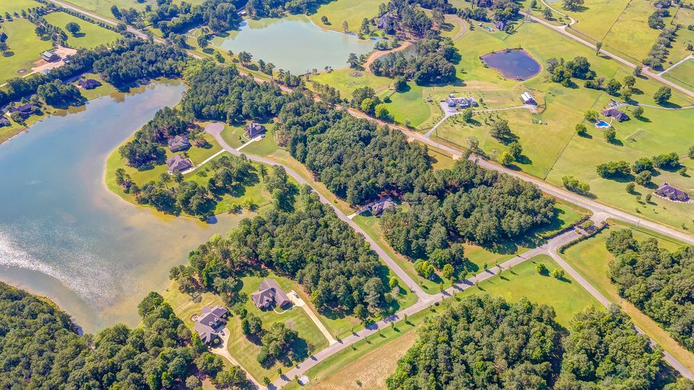 Aerial view of rural lakeside properties with winding roads through forested areas.