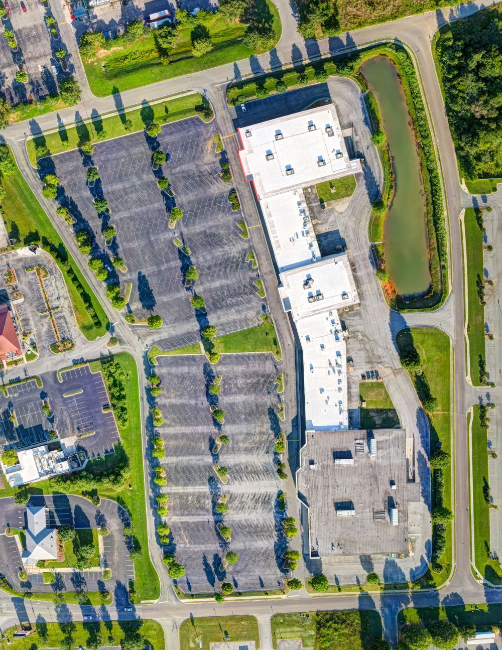 Bird's eye view of a large retail complex with extensive parking and landscaped borders.