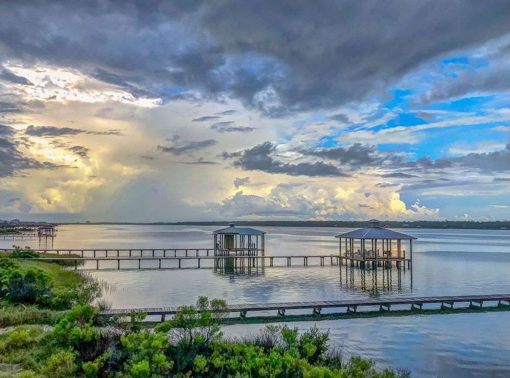 Dramatic sunset sky over a wooden pier and boat dock extending into calm waters.