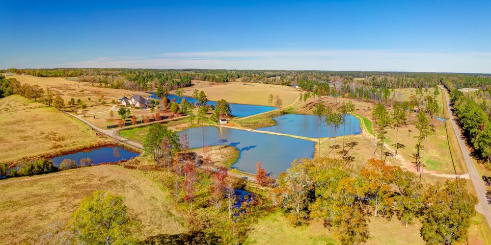 Drone shot of interconnected ponds and waterways surrounded by autumn trees and open fields.