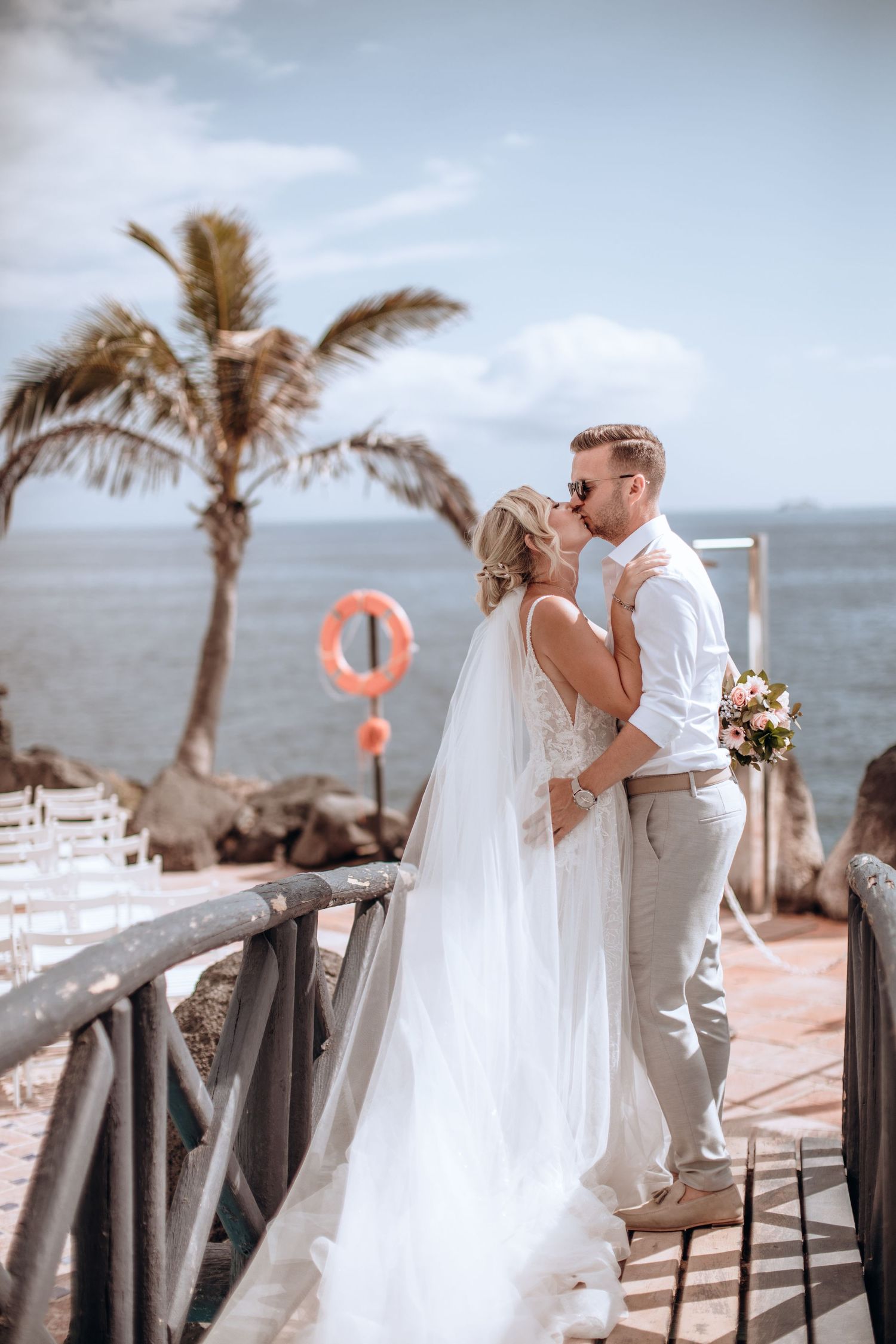 Bride and groom share a kiss against the picturesque backdrop of Tenerife's scenic seaside.