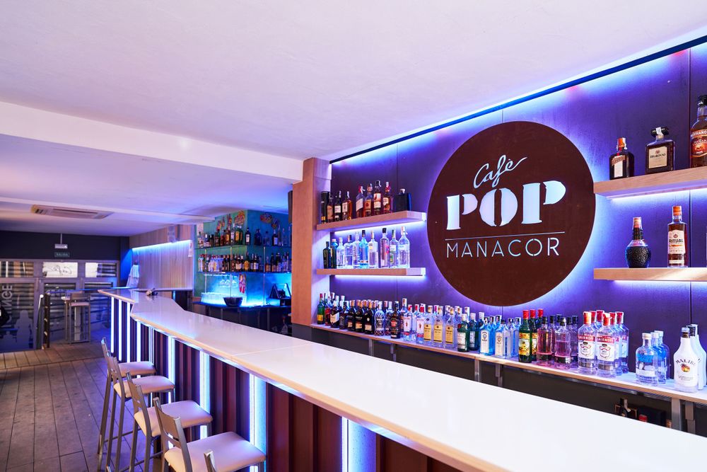 Modern bar interior with blue LED lighting and 'POP' signage displaying bottles on illuminated shelves.
