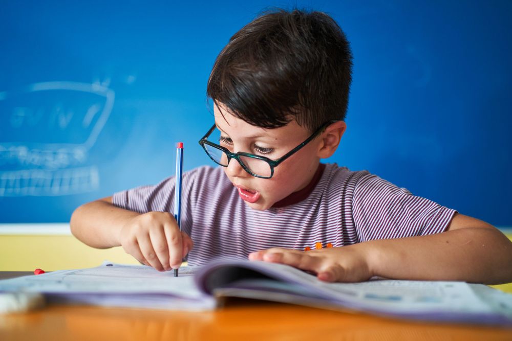 Student in striped shirt studying with focused concentration at desk.