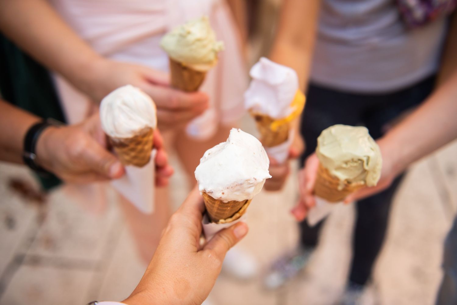 Multiple hands holding ice cream cones with various flavors.Gelateria Emiliana 2019