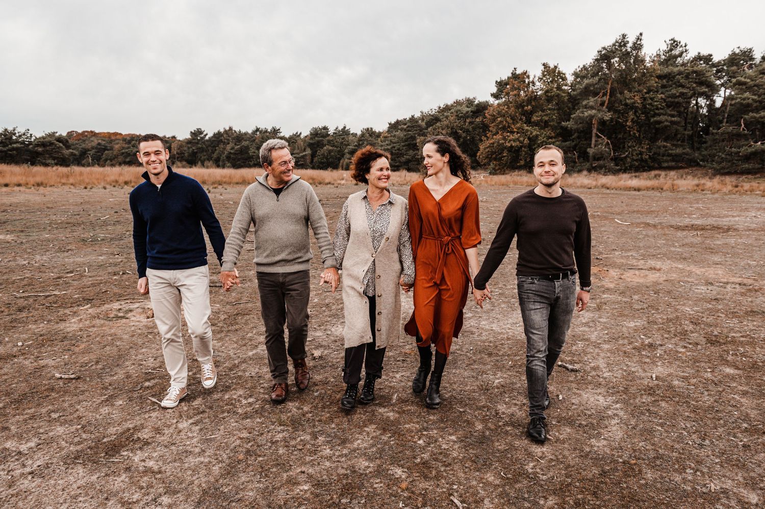 Group walking together through autumn field during golden hour photo session.