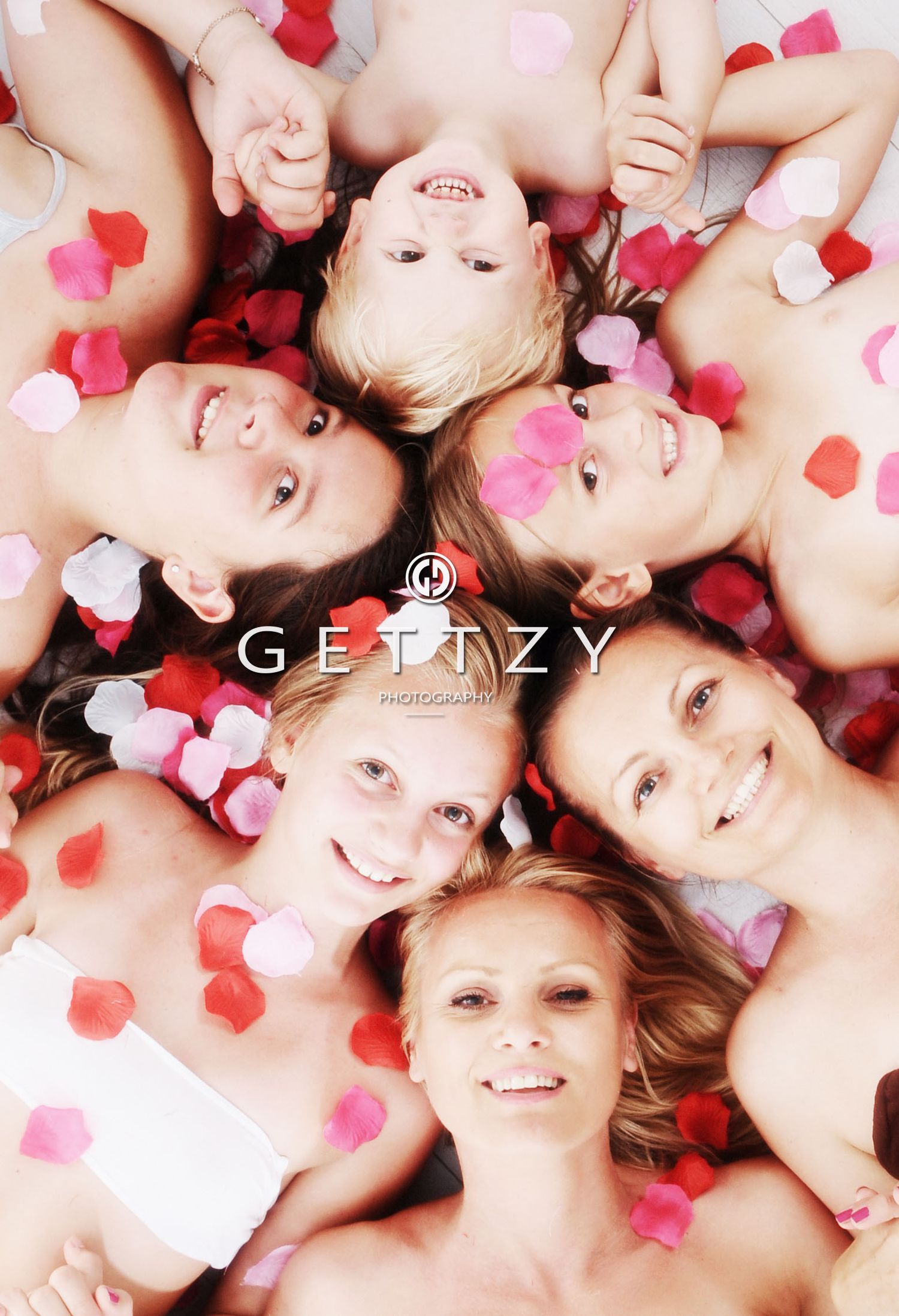 Circle of people lying down with scattered pink and red heart confetti.