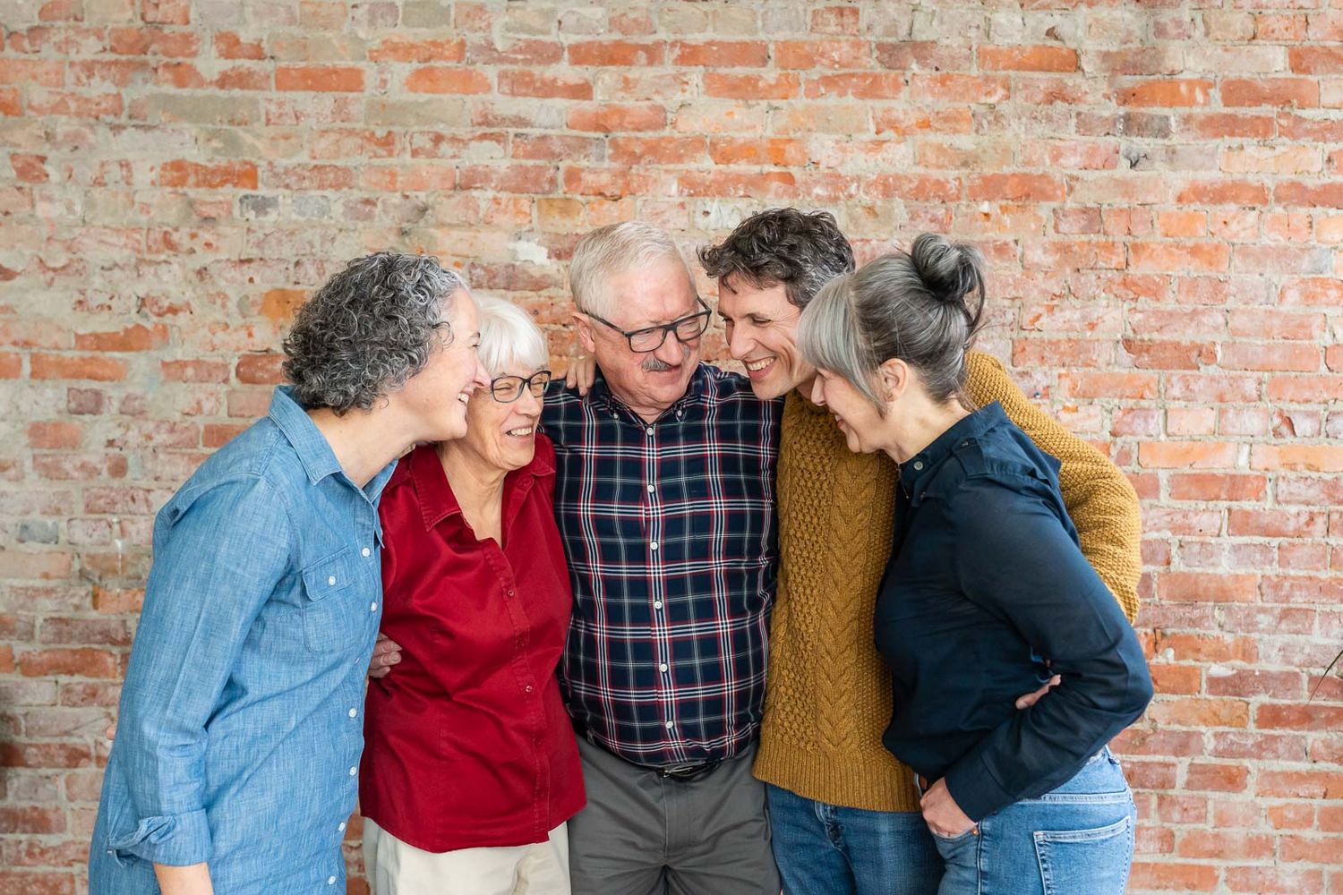 Grandparents with their adult children laughing in an indoor Seattle studio.
