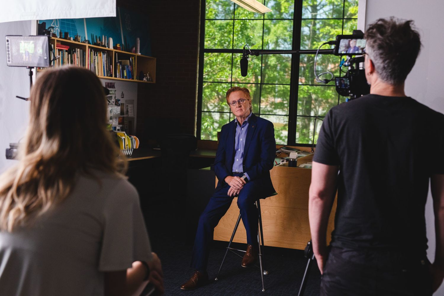 Interview filming setup in modern office with production crew and equipment.