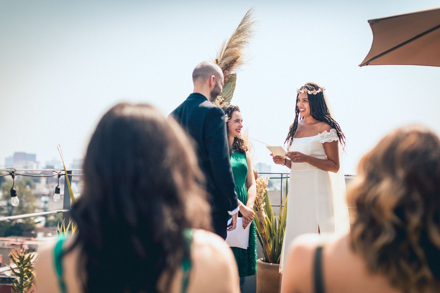 Outdoor celebration with guests enjoying beverages under patio umbrellas.