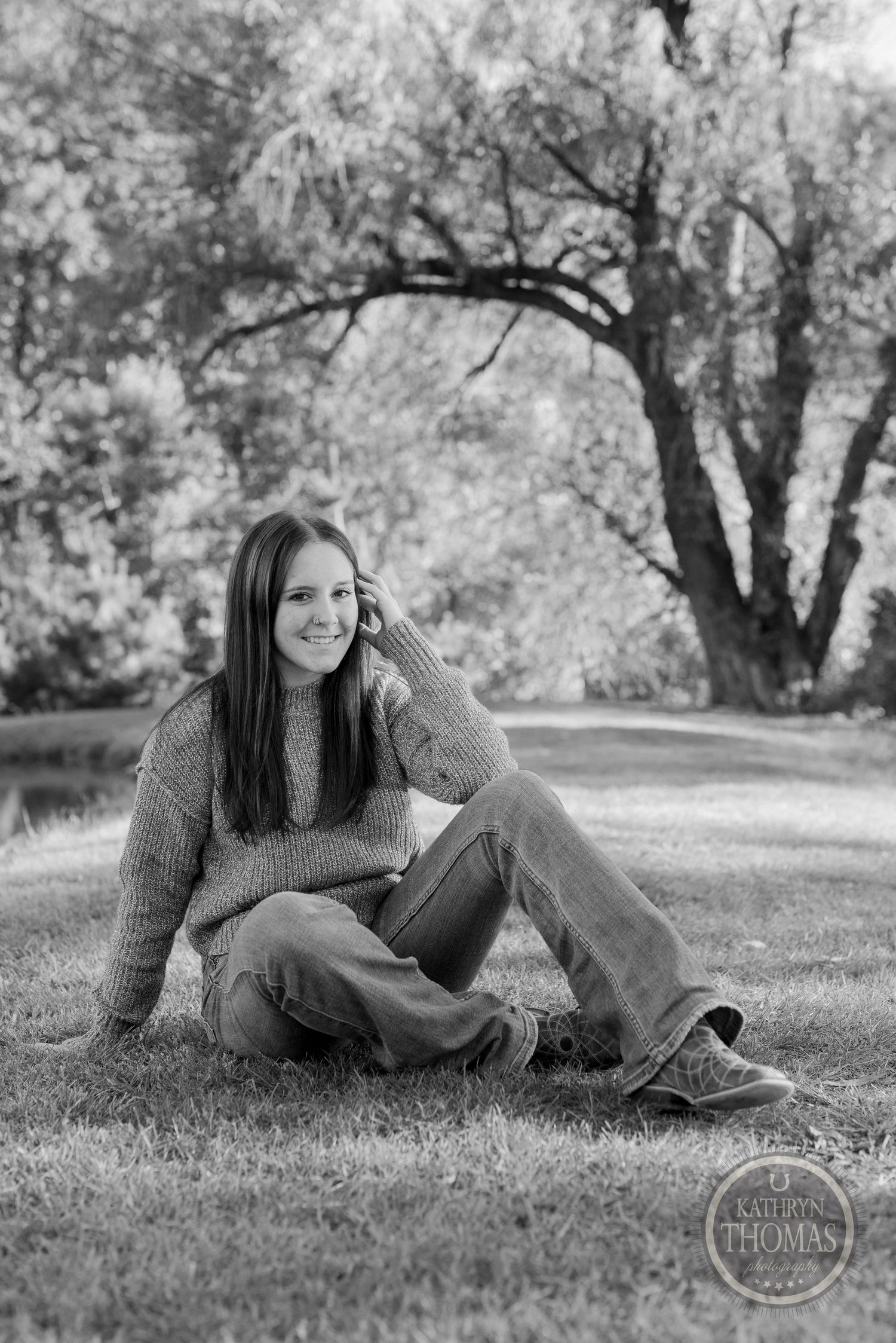 Black and white casual portrait taken on grass with trees creating a natural backdrop.