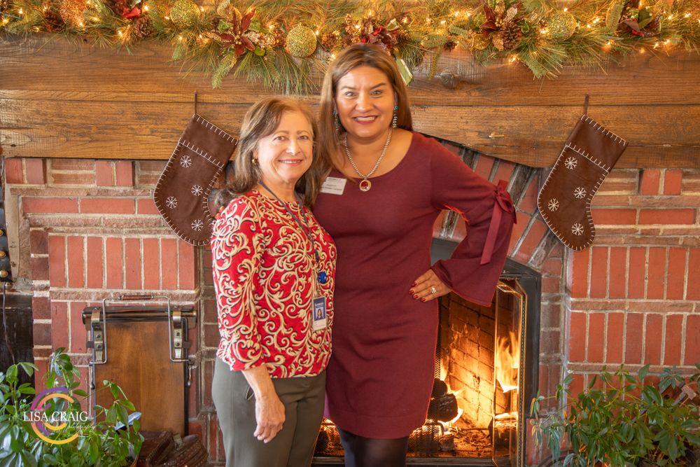 Two people smiling in front of holiday decorated fireplace with hanging stockings.