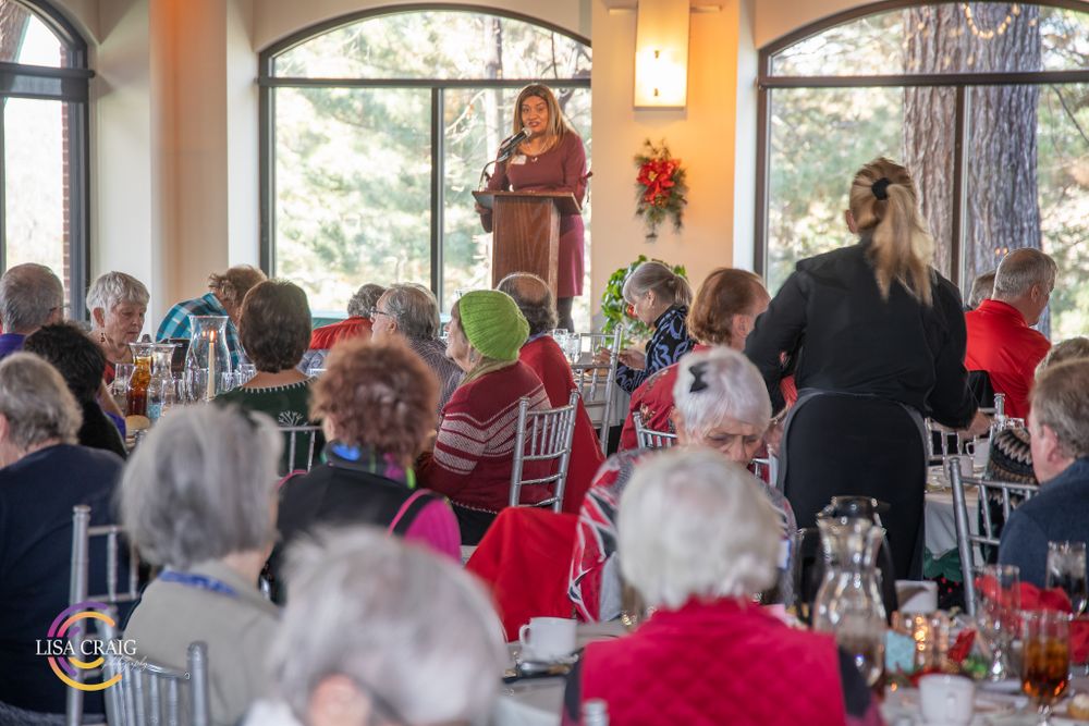 A speaker addresses a crowd in a banquet hall decorated for the holidays.