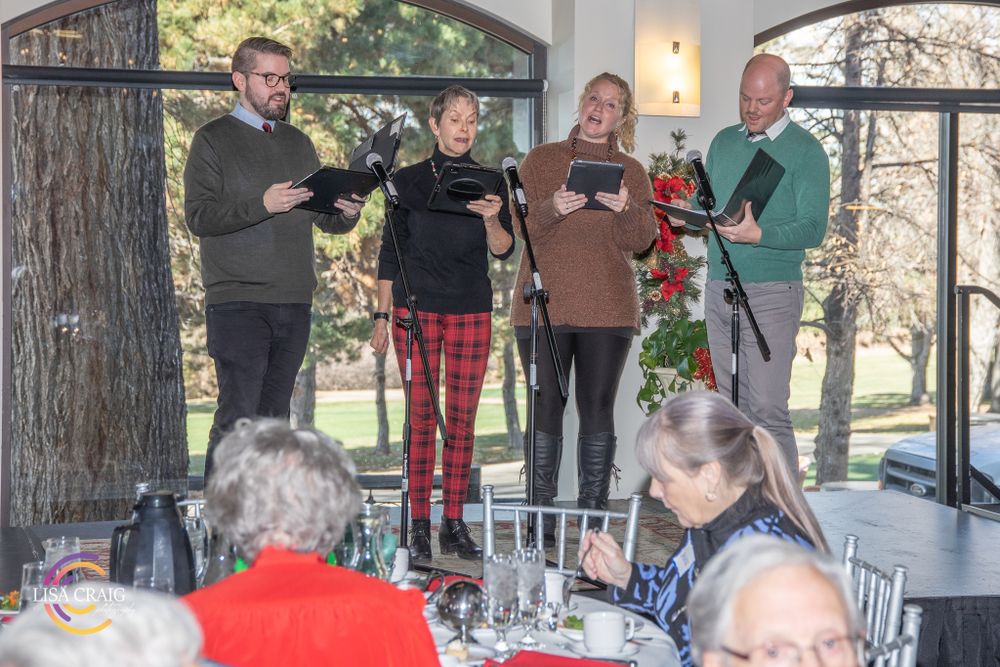 Four entertainers perform on stage during a holiday gathering.