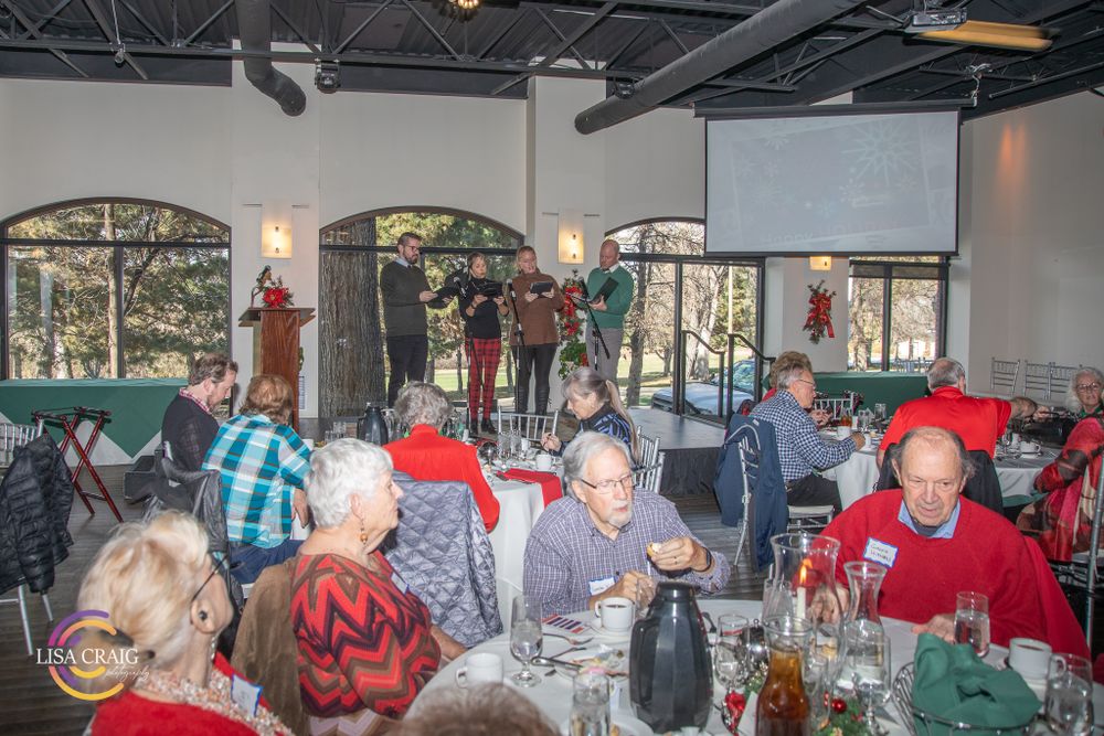 Performers entertain guests during a holiday banquet in a decorated dining hall.