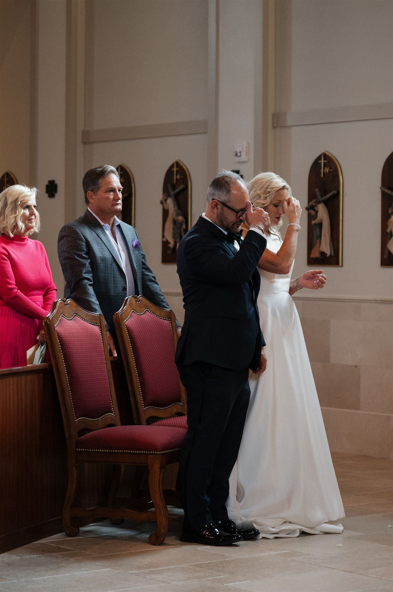 Wedding ceremony attendees gathered in an elegant church with arched windows and red chairs.