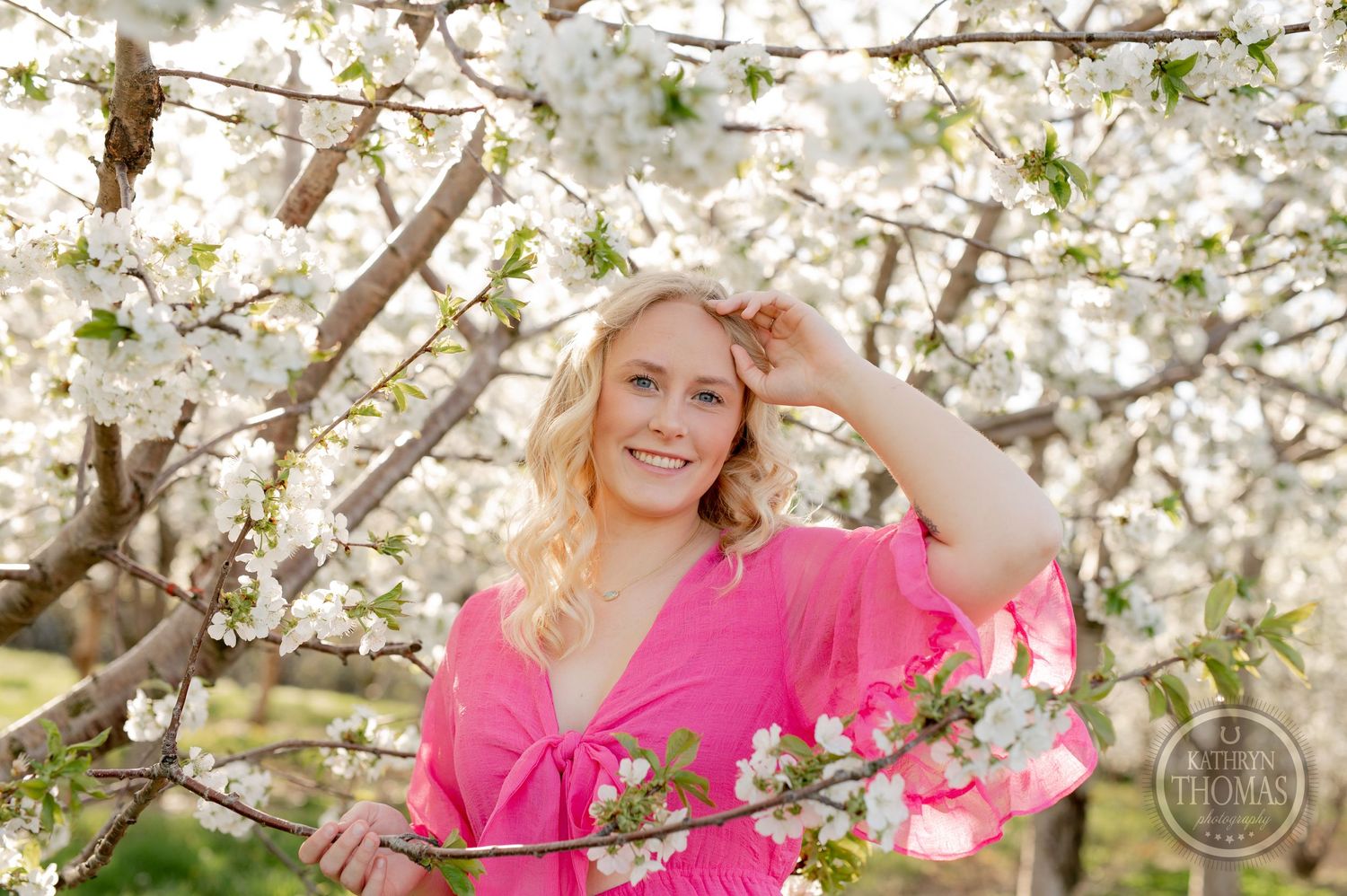 Romantic springtime portrait surrounded by delicate white cherry blossoms in an orchard.
