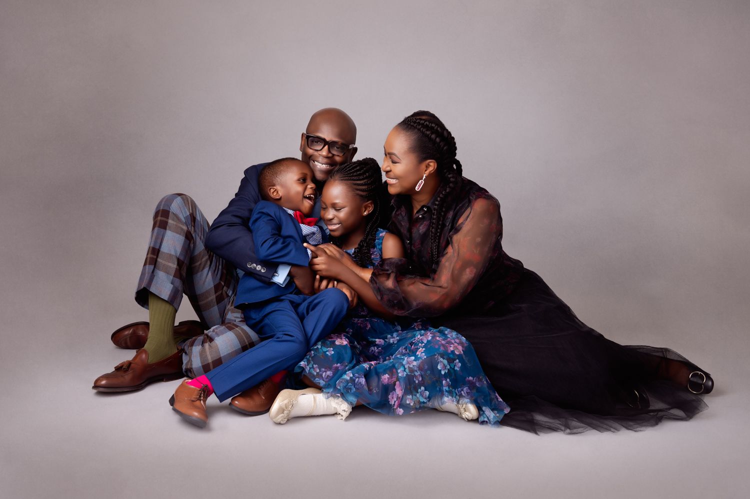 Family lounging together on studio floor in casual attire.