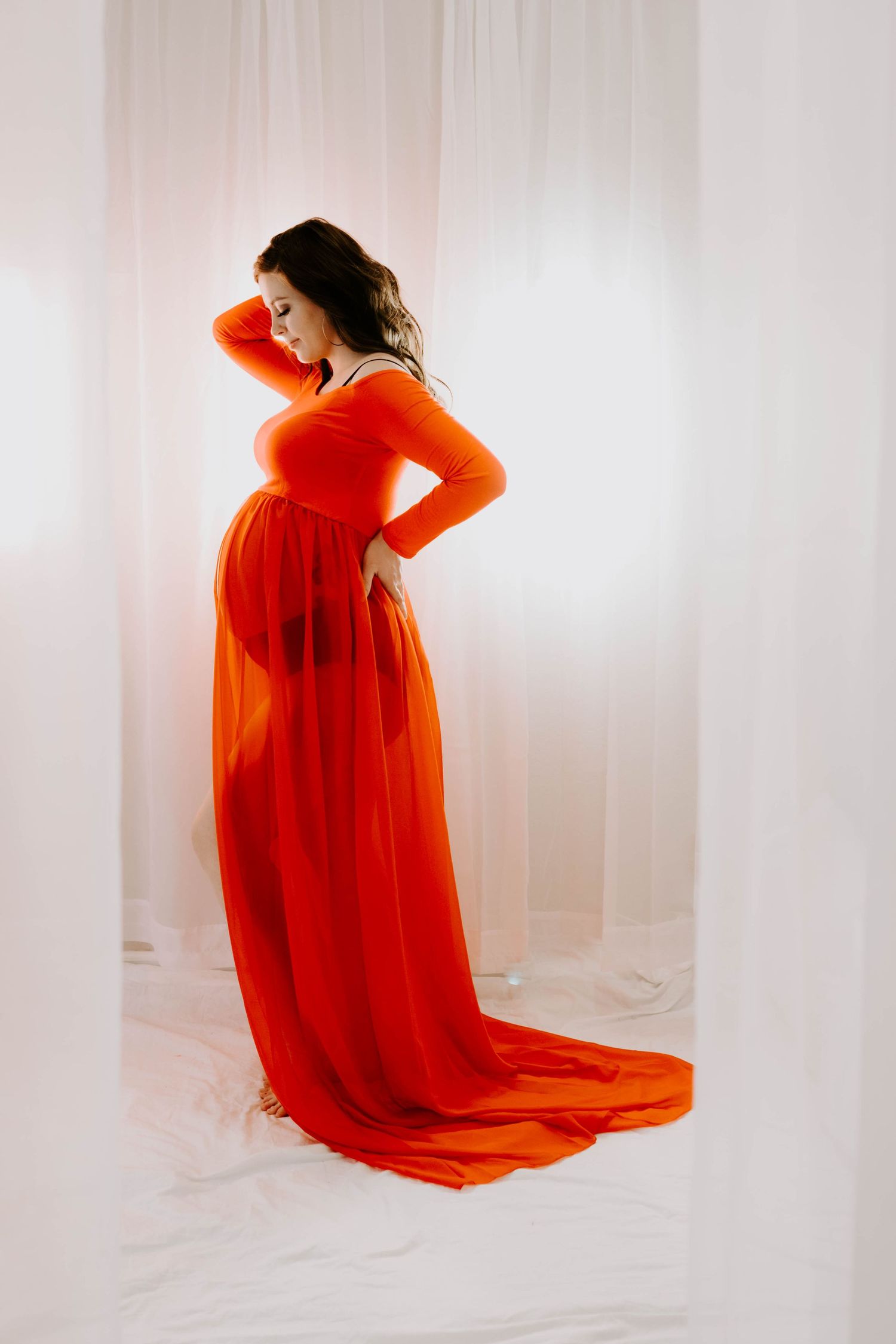 Artistic portrait of someone in a flowing red dress against a white backdrop.