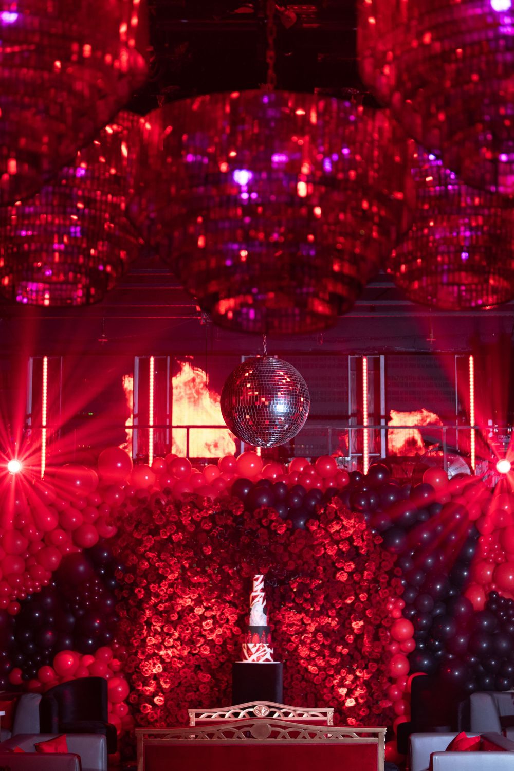 Disco ball reflecting purple lights above elegant venue decorated in red and black theme.